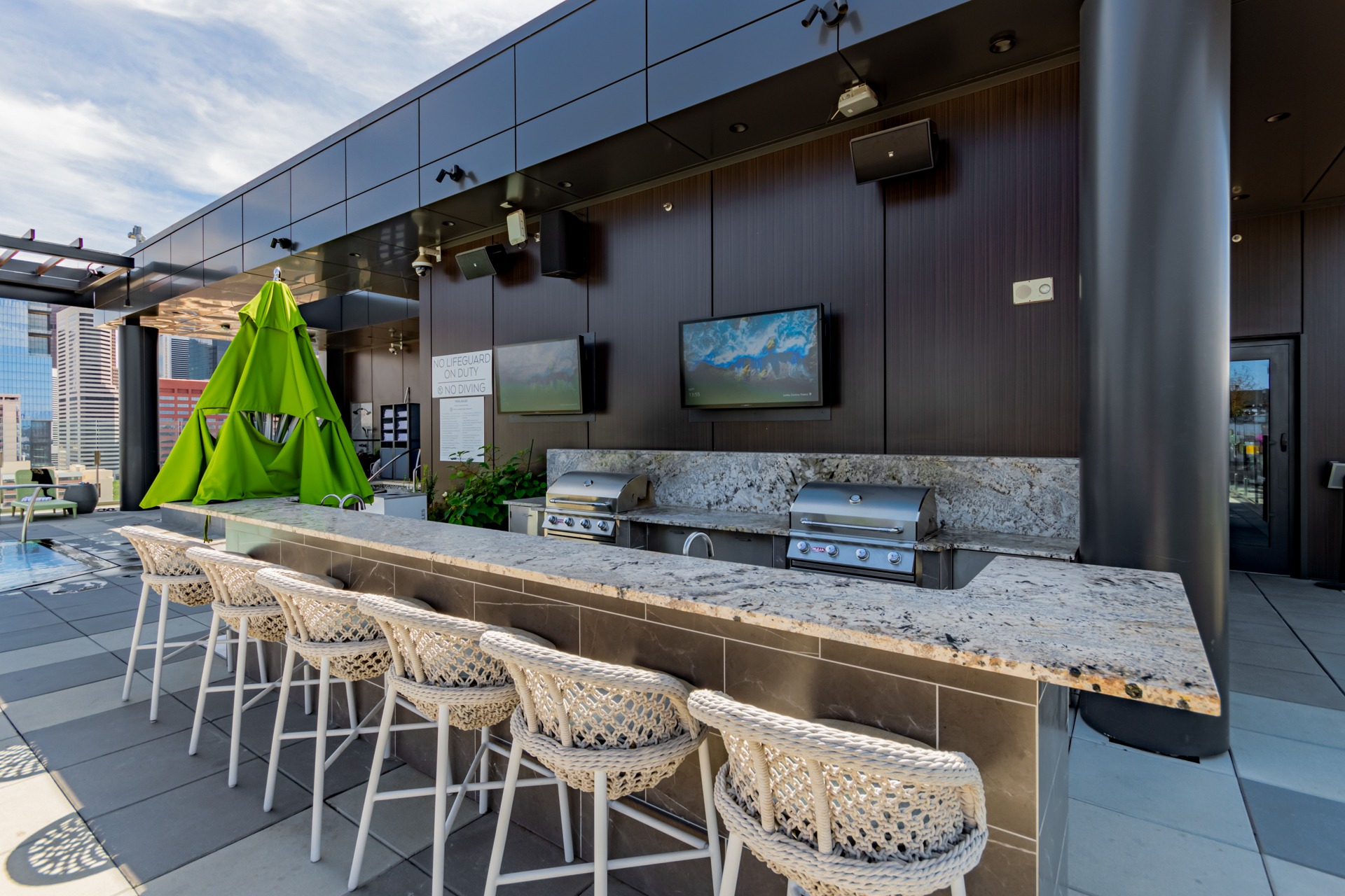 Rooftop outdoor kitchen with built-in grills, bar seating and televisions